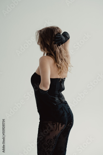 Photo of beautiful young woman in black dress back is turned. Long stylish gloves. Pretty face evening makeup, an elegant hairstyle