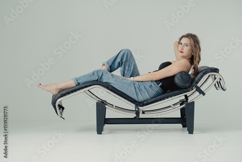 Photo of young beautiful woman lying on the couch in jeans and black corset.