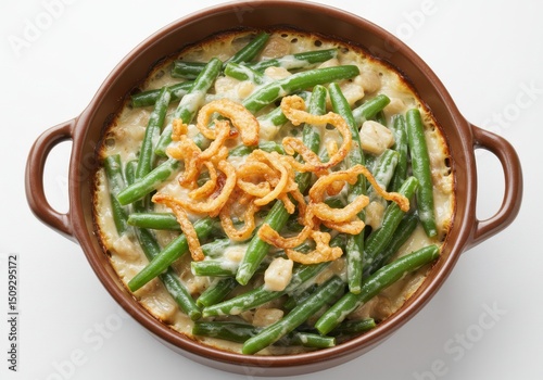 Overhead view of green bean casserole in a brown dish with fried onion topping on a white background