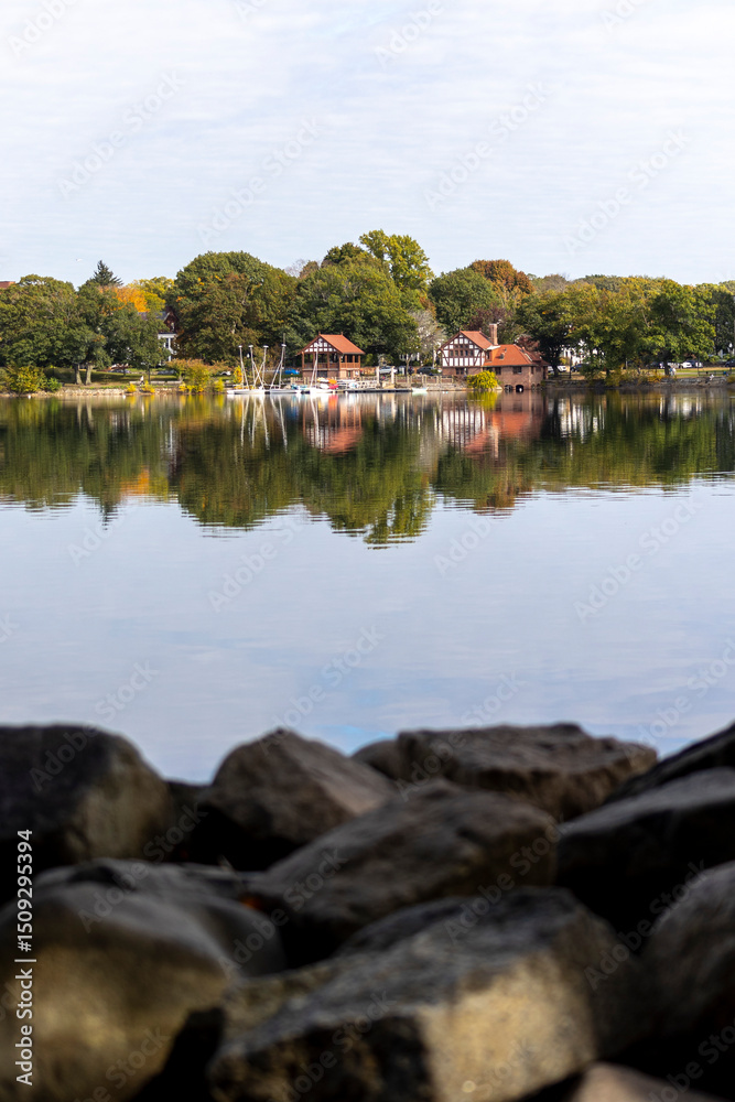 Boathouses and Sailboats Reflected in Still Water on a Calm Autumn Day Boathouses and Sailboats Reflected in Still Water on a Calm Autumn Day