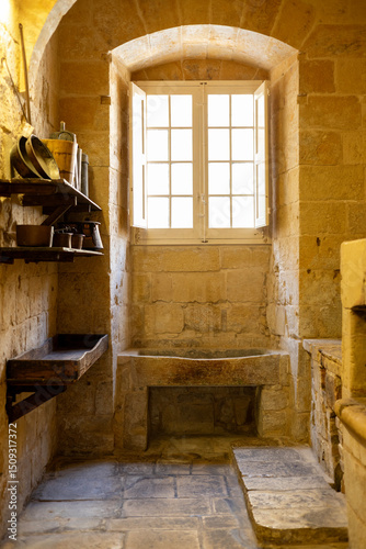 Billede på lærred Interior of an antique kitchen and scullery with heavy wall shelves made of wood, stone sink and utensils, with a window, on a bright summer day