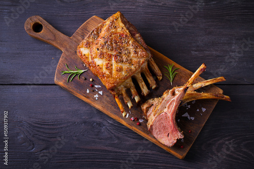 Roasted rack of lamb. Lamb chops on serving board and black wooden background. High angle view