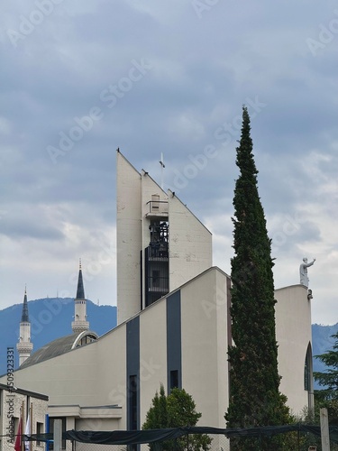 view of a church in downtown Tirana with towers of a mosque in the background on a cloudy summer day
