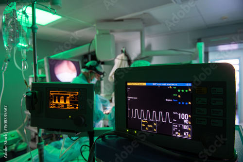 A detailed shot of anesthesiology equipment in a dimly lit operating room showcases intricate controls and monitors, highlighting the precision involved in patient care.