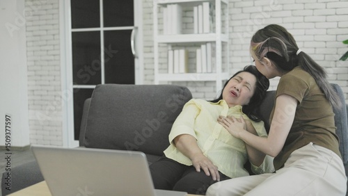 Elderly Asian woman suffers chest pain while working on laptop