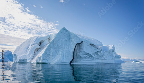 Large  iceberg with deep crevasse and dramatic sky in Disko Bay in Greenland photo