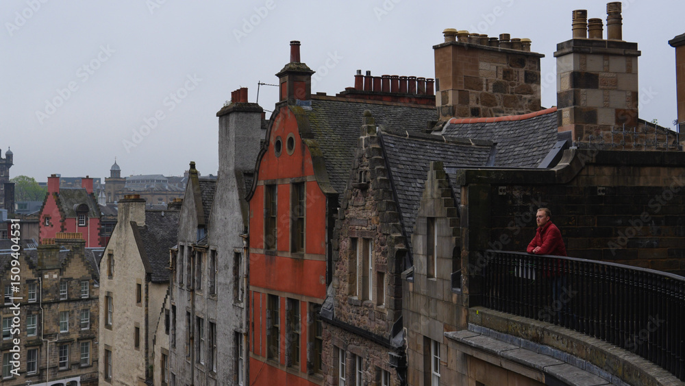 Naklejka premium Man on balcony admiring the beautiful medieval city of Edinburgh, Scotland UK
