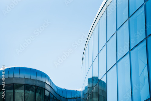Contemporary architecture building with glass and metal facade on clear blue sky. For illustrating urban design or modern construction concepts. Copy space for text