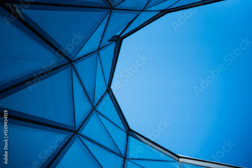 Contemporary architecture building with glass and metal facade on clear blue sky. For illustrating urban design or modern construction concepts. Copy space for text