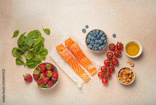 Raw salmon fillets, spinach, strawberries, blueberries, cherry tomatoes, almonds and olive oil. Set of foods that help to reduce inflammation, top view