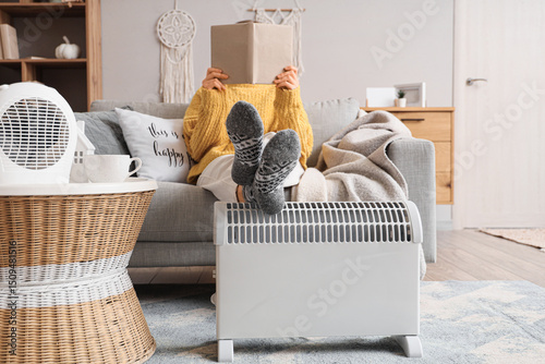 Young woman warming legs on...