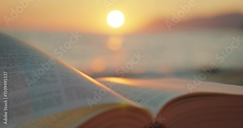 Open book on a beach illuminated by sunset light in summer warm evening