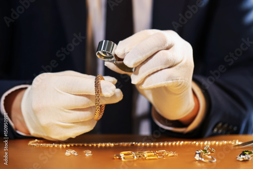 Obraz na płótnie Appraiser with loupe evaluating luxury jewelry at table, closeup
