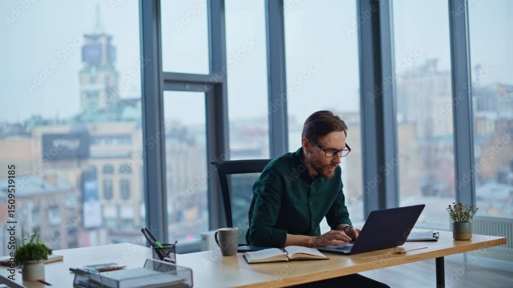 Excited businessman reading email at laptop enjoying success in modern workspace