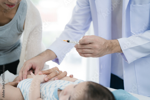 Asian loving mother comforts her three-month-old, as a male doctor administers essential childhood vaccinations, ensuring the baby's healthy future in a calm, professional setting.