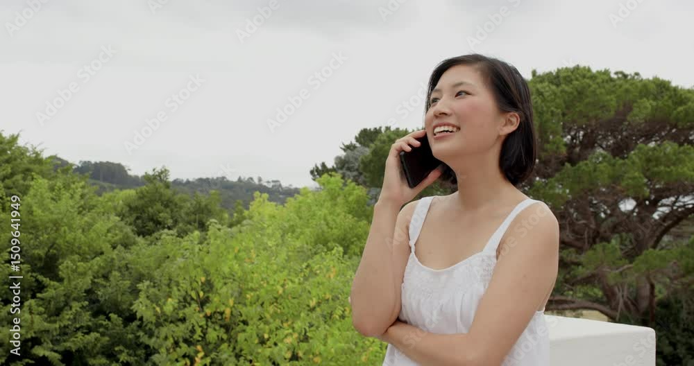 Answering call, Asian woman walking on white terrace holding smartphone laughing and listening Answering call, Asian woman walking on white terrace holding smartphone laughing and listening
