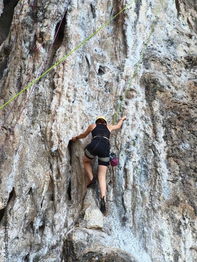 climber on the top Female athlete top rope rock climbing at Railay Beach, Ao Nang, Krabi Province, Thailand. climber on the top Female athlete top rope rock climbing at Railay Beach, Ao Nang, Krabi Province, Thailand.