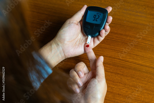 Woman's hands checking diabetes and hyperglycemia with digital blood sugar meter. Healthcare and medical concept	