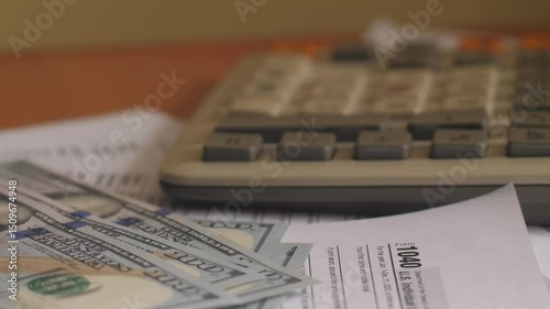 financial reporting and tax payment, featuring a tax form 1040, a calculator, and U.S. dollar cash bills.  calculations, monetary transactions, and responsible financial management