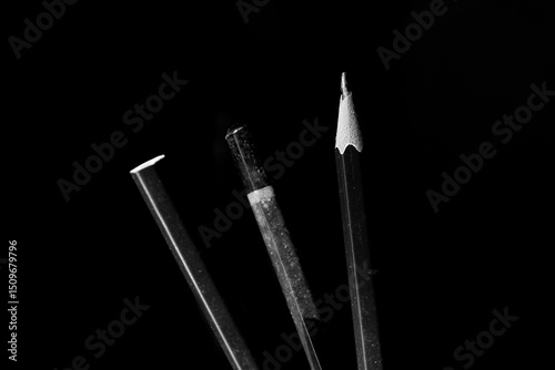 Sharpened Red Pencil Standing Out Among Black Pens in Dramatic Low Light
 photo