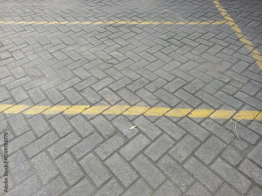 Fototapeta premium Gray Paving Stones with Yellow Parking Lot Lines