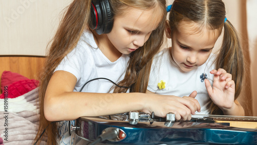 Wallpaper Mural Two girls are sitting on the bed with a electric guitar. The older sister teaches the younger to play the guitar. Torontodigital.ca