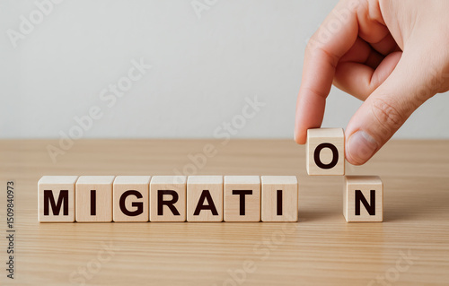 Hand placing last wooden block with letter, completing migration word, representing moving, relocation, immigration, change, adaptation, travel, opportunity, future