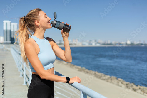 Foto Sport woman jogger runner drinking water from bottle at city embankment river cl