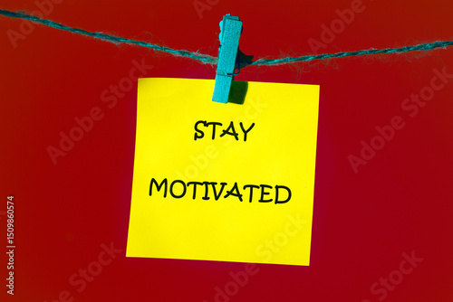 Business, support, motivation, psychological concept. STAY MOTIVATED written on a bright yellow note, which is attached to the shoelace with a blue clothespin on a bright red background
