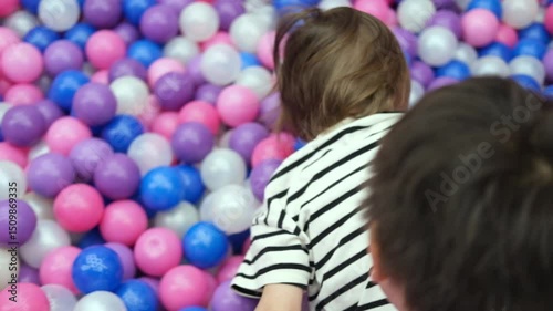 Happy child, toddler boy is playing, having fun in the entertainment center with colorful multicolored plastic balls in the pool. photo
