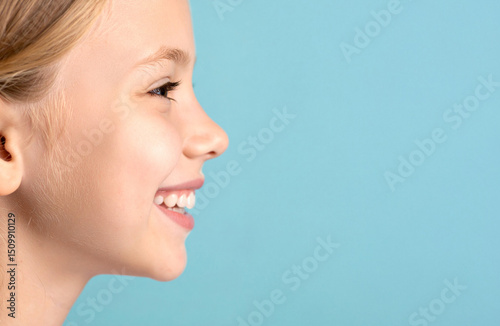 Close-up of the profile of the child smiling lovingly against the teal color background.