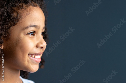 Close-up of the profile of the child smiling lovingly against the dark background.