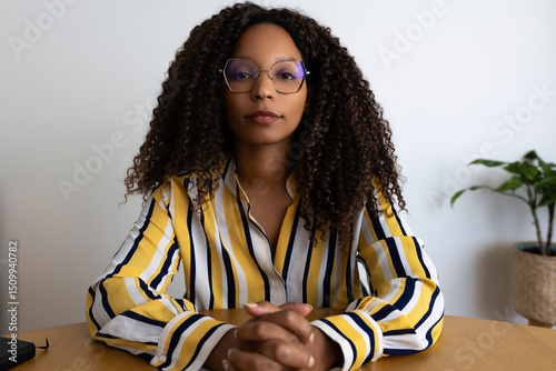 Black woman looking at camera with serious expression during video call.