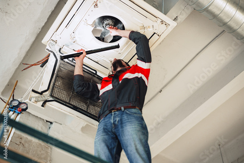 Фотография Technician repairs air conditioning unit in commercial building during afternoon