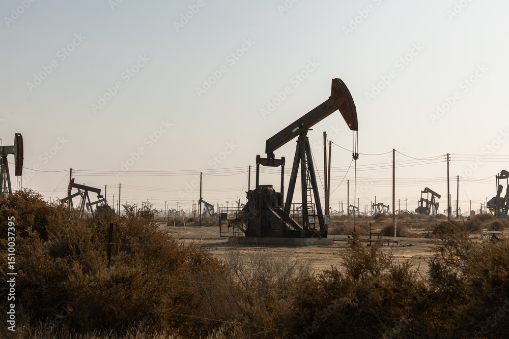 An oil drilling platform stands tall in the heart of the California desert, surrounded by arid, sandy terrain and sparse vegetation An oil drilling platform stands tall in the heart of the California desert, surrounded by arid, sandy terrain and sparse vegetation