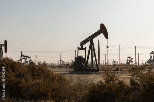 An oil drilling platform stands tall in the heart of the California desert, surrounded by arid, sandy terrain and sparse vegetation