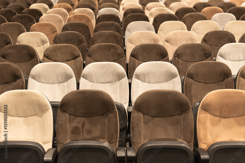 Naklejka premium Rows of empty auditorium chairs in soft neutral tones, creating a symmetrical pattern ideal for concepts of events, gatherings, or public spaces.