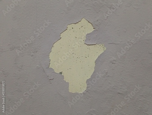 The paint on the wall is peeling off in large sections, showing an uneven yellow layer beneath the faded purple topcoat.