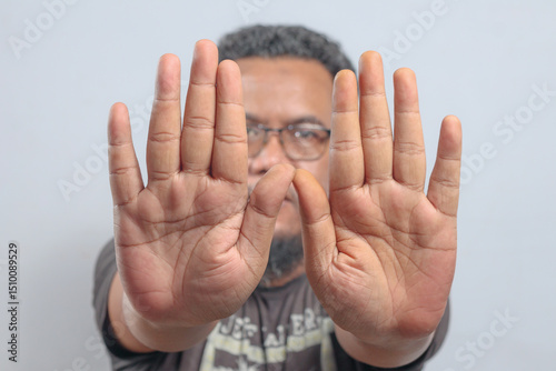 Man raises both hands forward with open palms in clear refusal or defensive stop gesture emphasizing alert or warning action