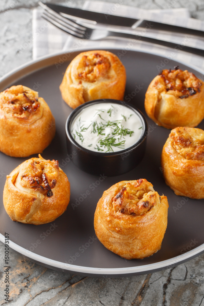 Fototapeta premium Knish or knysh is a traditional food of Eastern European consists of a filling covered with dough that is baked closeup on the plate on the table. Vertical