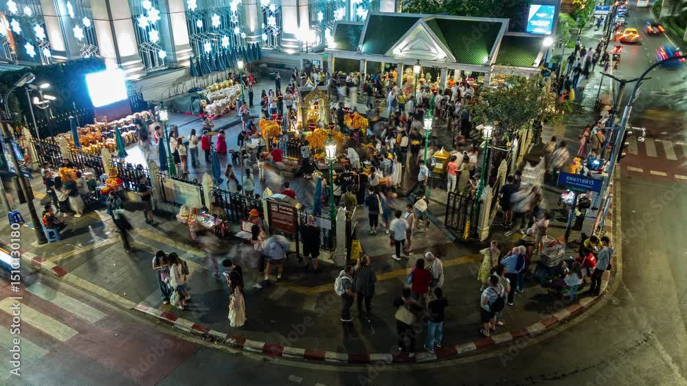 timelapse bustling scene at the Erawan Shrine in Bangkok at night. Crowds of pedestrians navigate the lively streets surrounded by colorful lights and local vendors. Energetic atmosphere filled with l