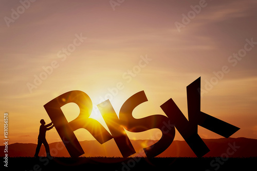 Photography Silhouette of person pushing large word RISK against backdrop of sunset