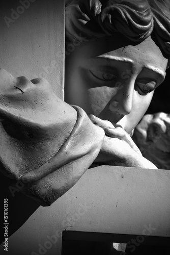 Close up ancient white statue of angel with cross as symbol of Christianity, death and resurrection of Jesus Christ. Close up.