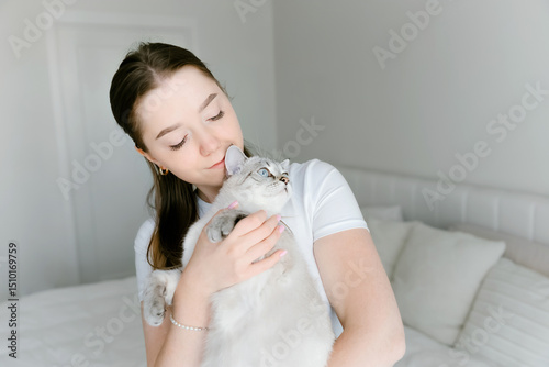 Woman cuddling fluffy cat in bright bedroom