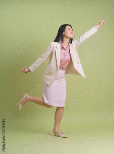 Woman celebrating joyfully in a light-colored suit against a soft green backdrop