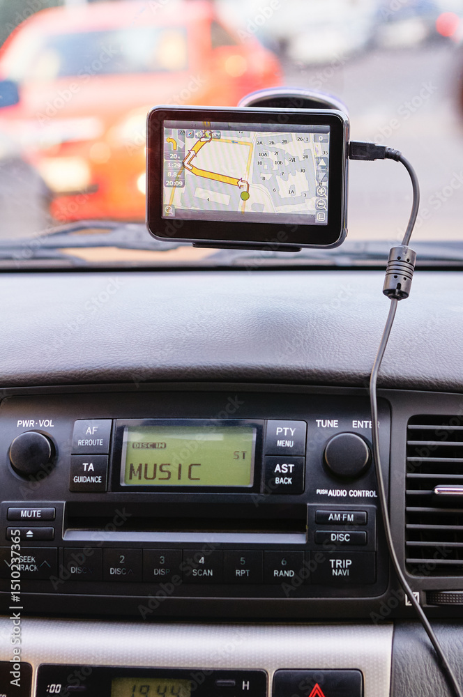 Fototapeta premium View of a car's dashboard featuring a GPS device displaying a route and an audio player interface labeled 'music.' Modern driving technology and convenience emphasized.