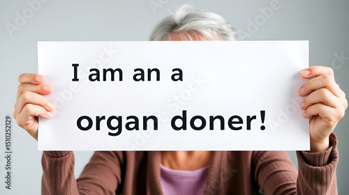 Organ donation concept: mature woman holding up a white sign with the text I am an organ donor in german.