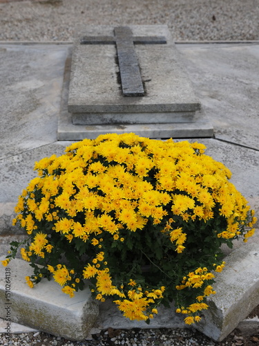Cemetery in Northern Italy, grave with large vase of yellow flowers.