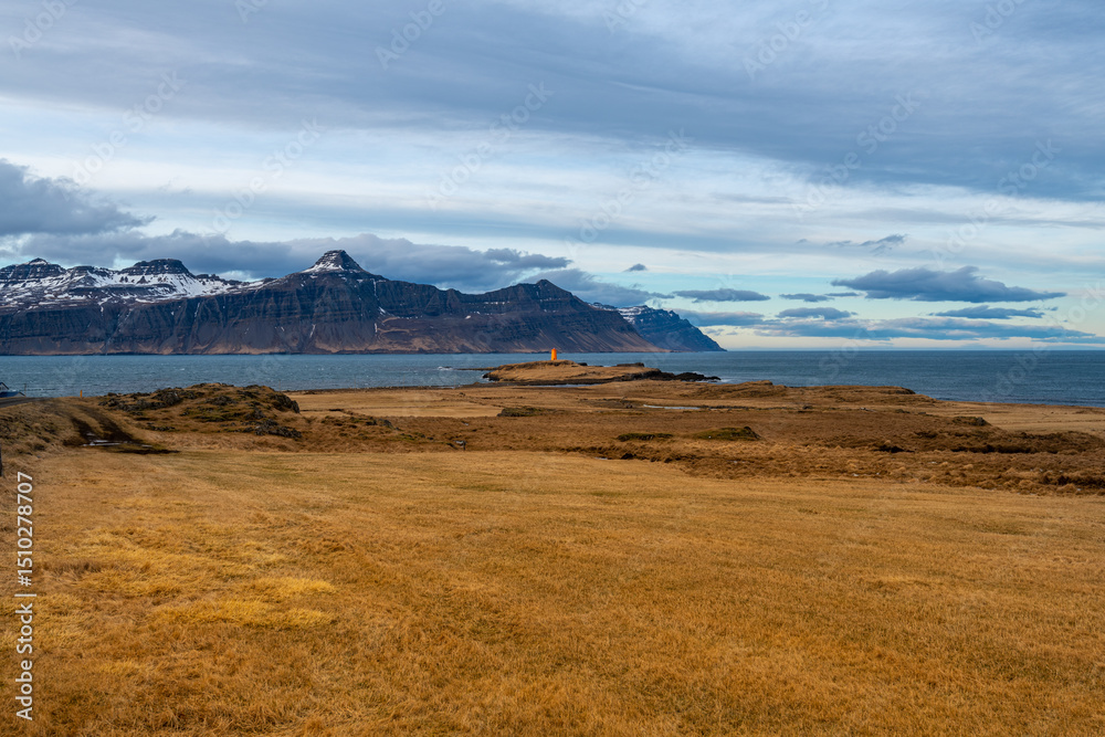 Fototapeta premium Icelandic Coastal Landscape with Lighthouse and Snow-Capped Mountains