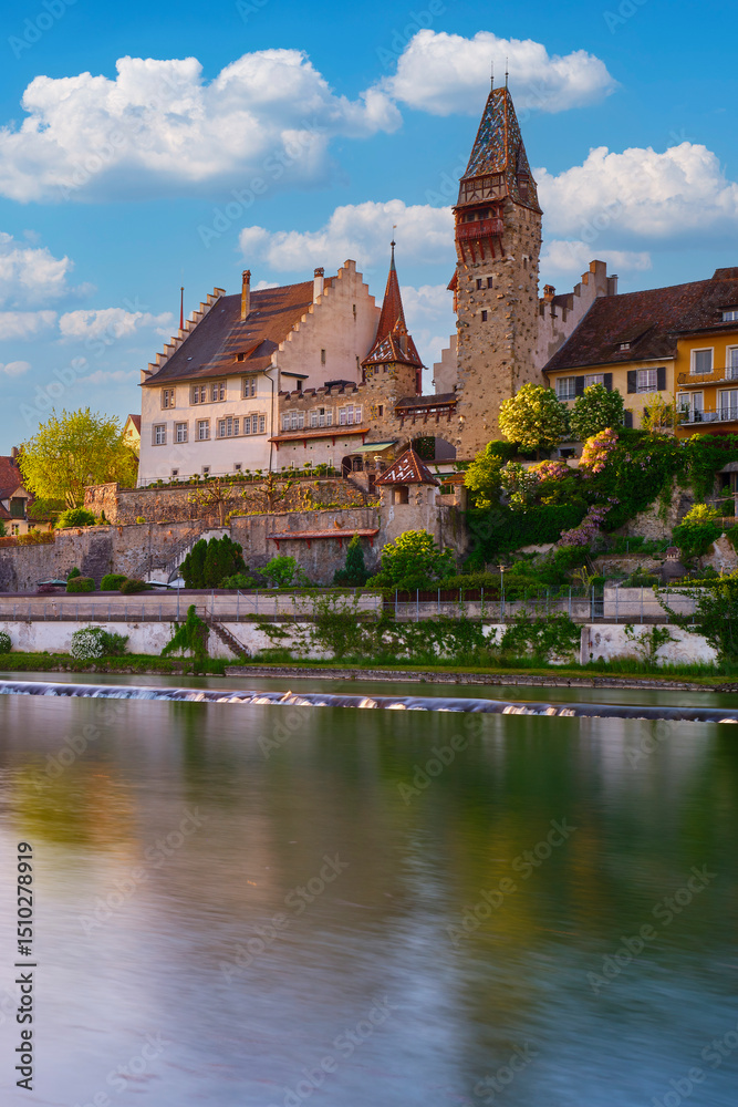 Fototapeta premium Historic castle overlooks tranquil river under a bright blue sky in the late afternoon